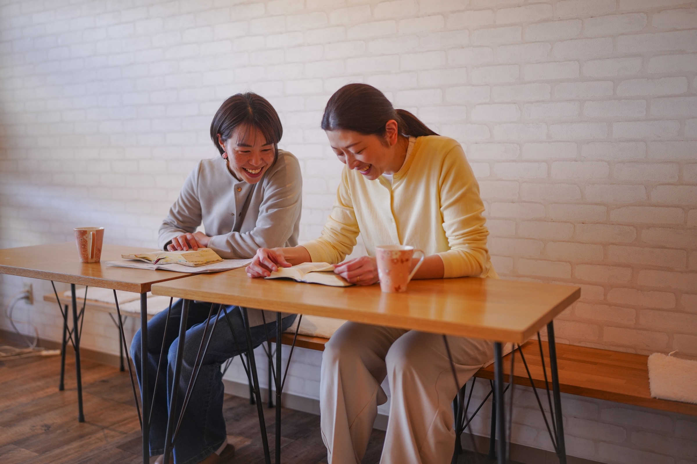 カフェで相談しながら笑顔で話す女性たち